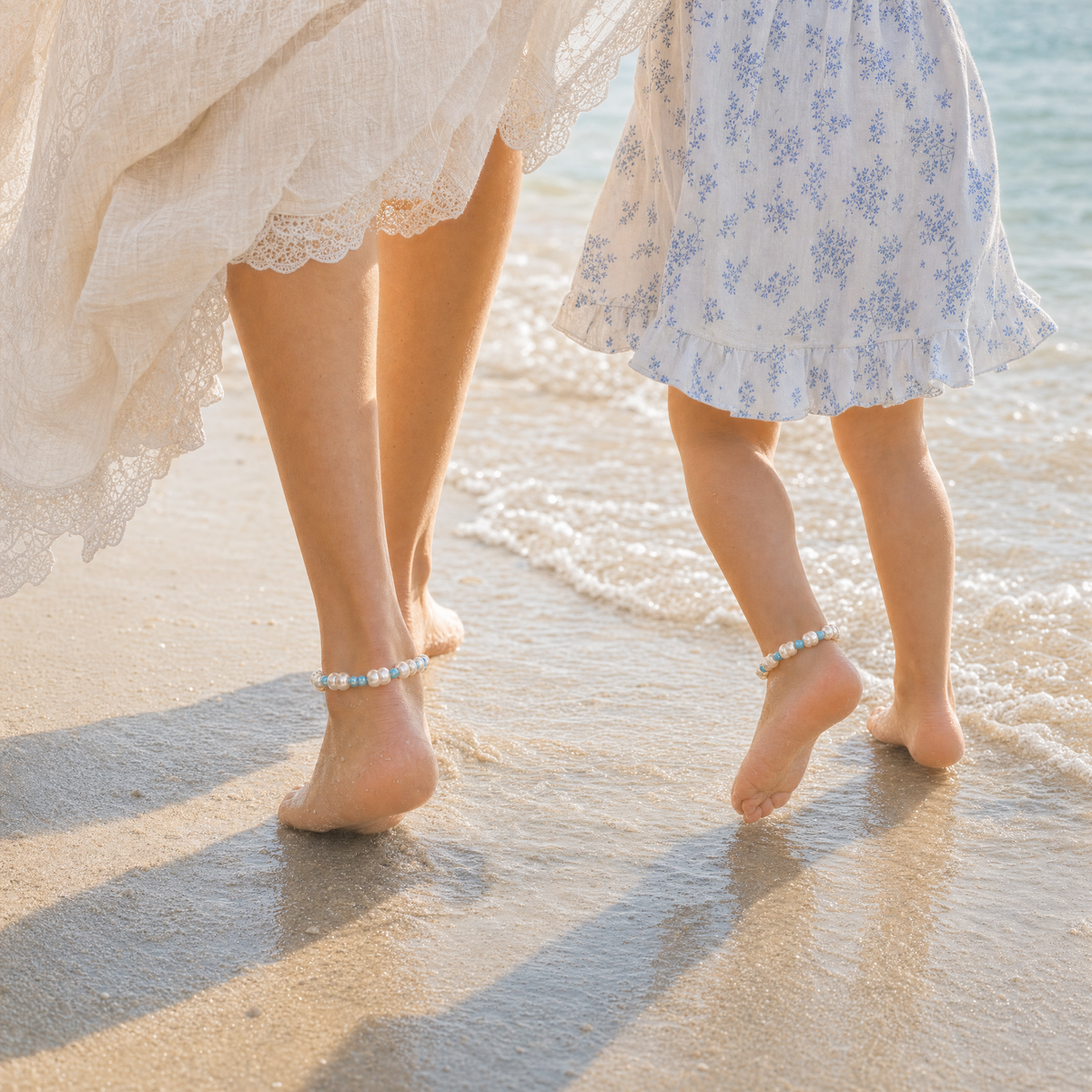 Mother and daughter walking on the beach wearing matching pearl and blue-bead anklets