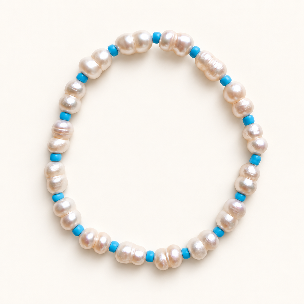 Daughter pearl stretch anklet with bright blue beads on a warm ivory background