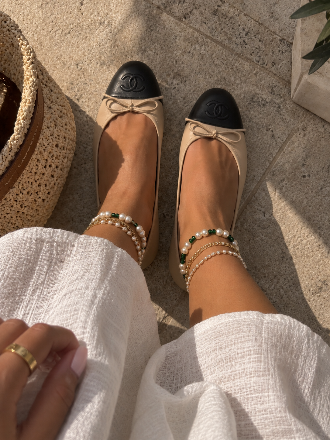 Green bead and pearl anklets styled with layered jewelry and ballet flats